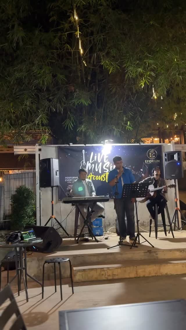 Tiga musisi tampil akustik di panggung EFORIUM pada malam hari
